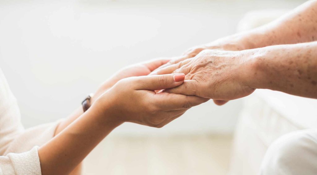 Calm Seas Home Care - Calm Seas Home Care Caregiver gently holding an elderly person's hand in support